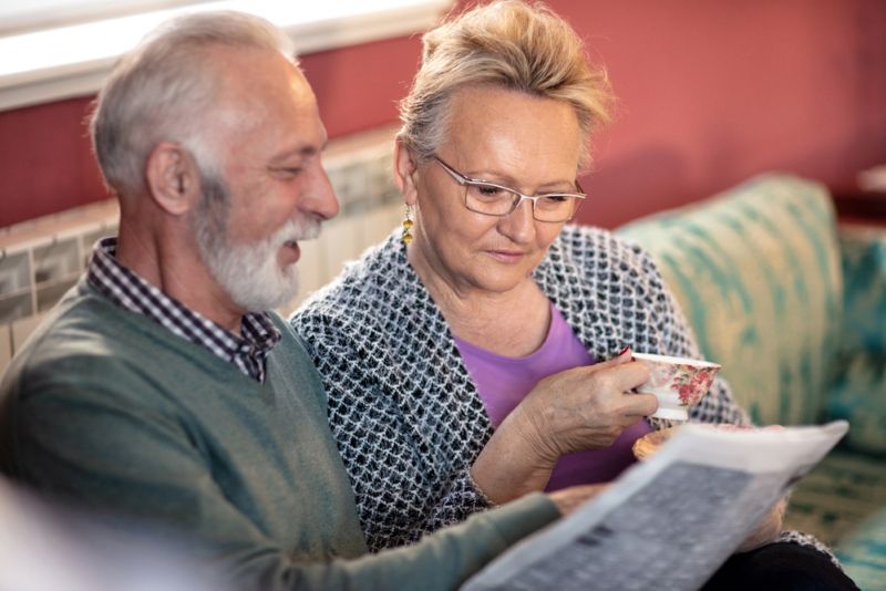 older man reading newspaper with a friend