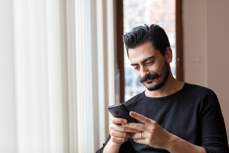 young man with moustache using phone