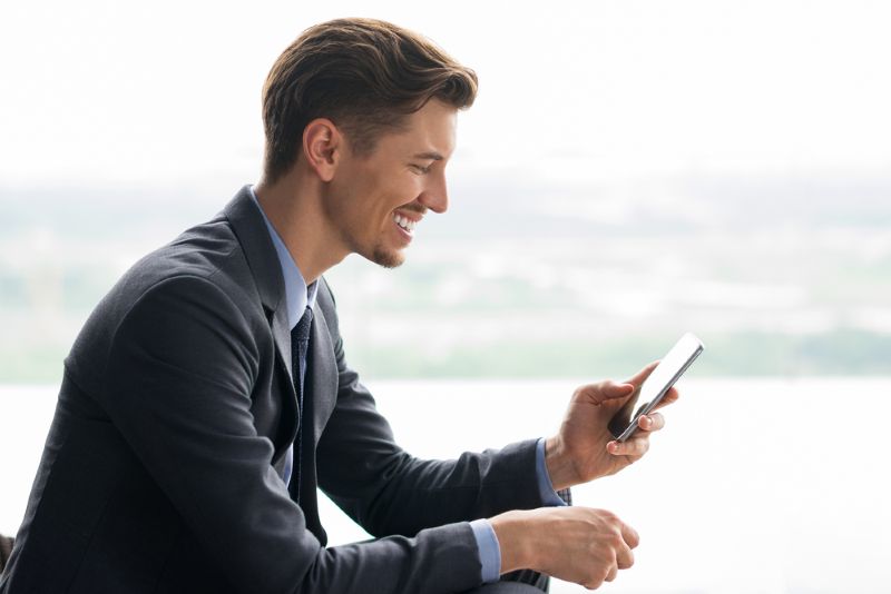 businessman smiling at his cell phone