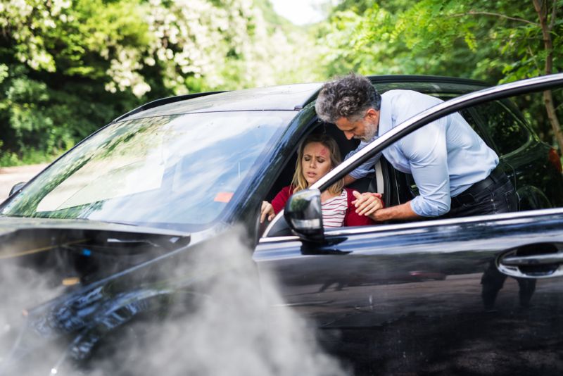 A man helping another woman out of her car after an accident